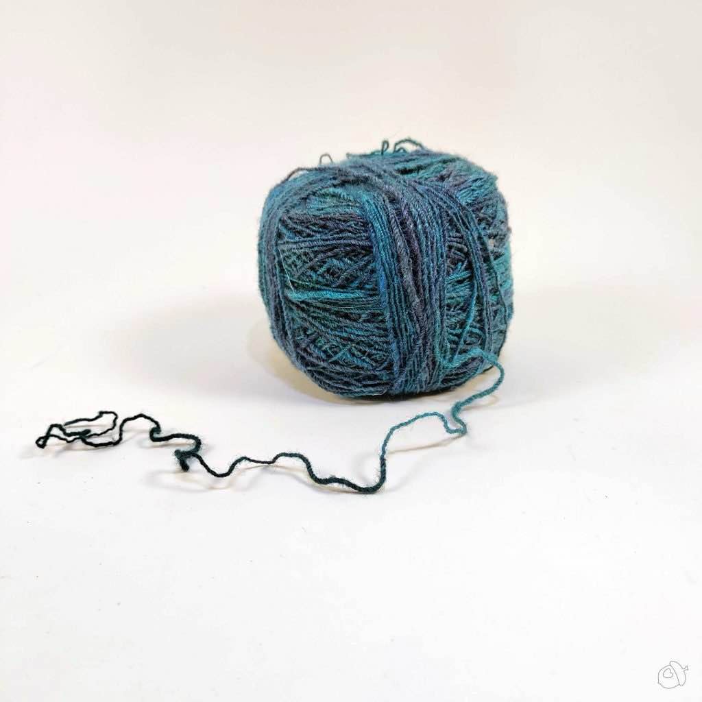 Cake of dark teal handspun on plain white background
