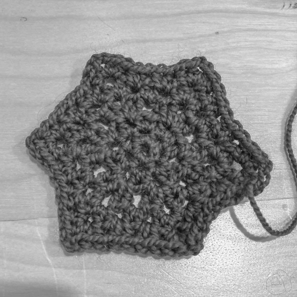 black and white of crochet hexagon motif shown on a wooden surface. this is to show the stitch texture.