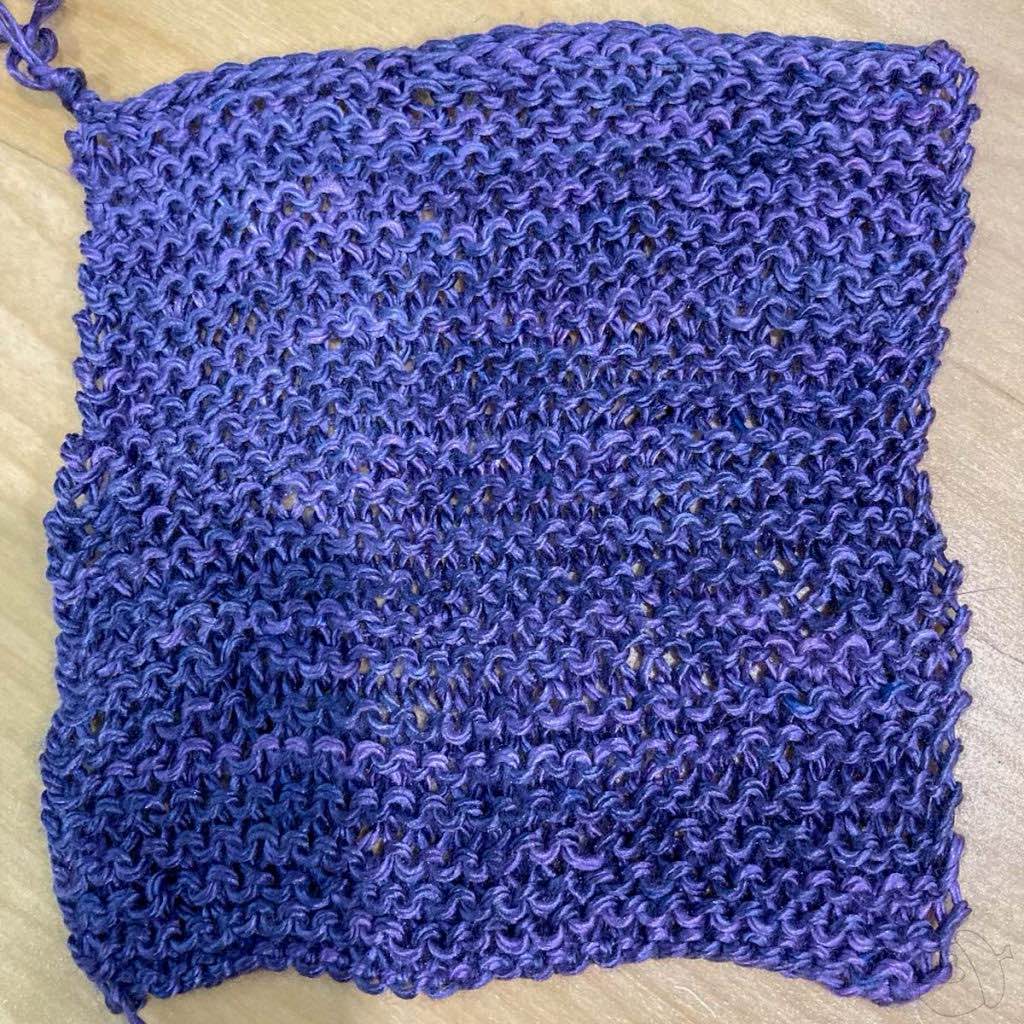Garterstitch swatch of Artyarns Silk day dream shown on a light wooden surface. The swatch is not blocked and it's not perfectly square.