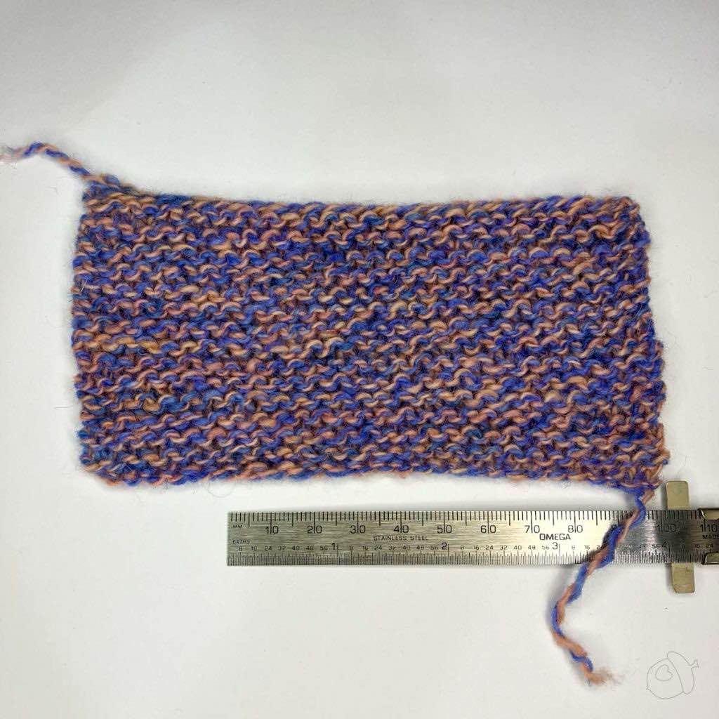 blue/pink marled yarn garterstitch swatch in Plied North Ave, blocked it is on a white background next to a ruler showing approximately 4 in / 10 cm width.