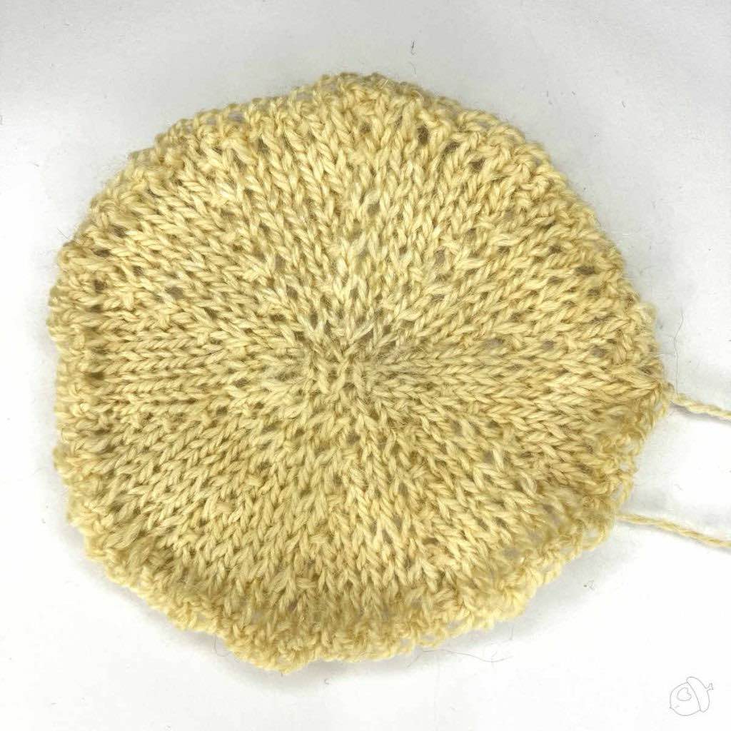 stockinette knit circular swatch. the yarn color is off-white the background is white.