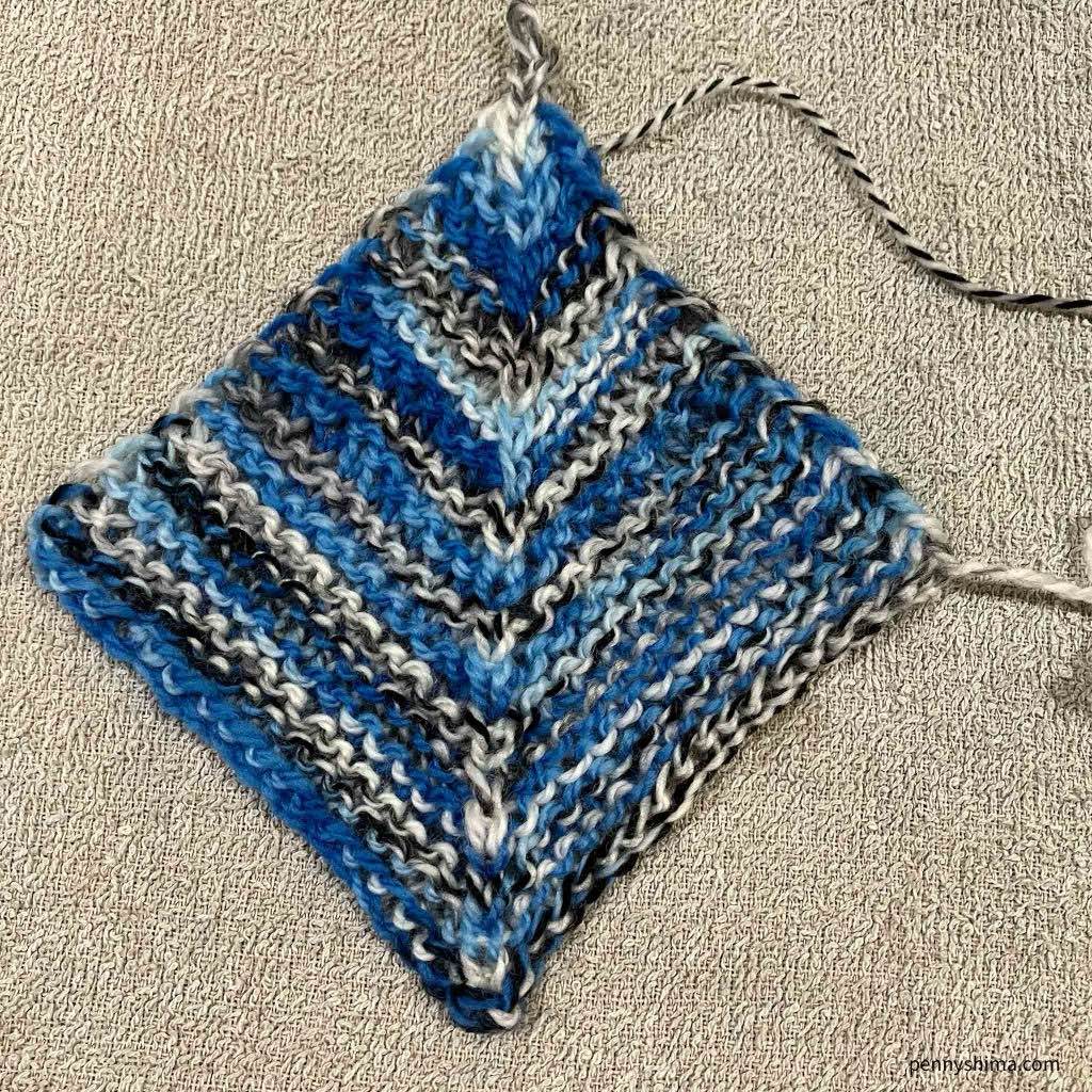 Miter square in blue zebra stripe yarn Shown lightly blocked on a light colored towel.