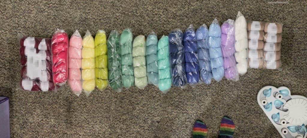 cotton blend yarns arrayed in a rainbow on a multi-brown carpet.
